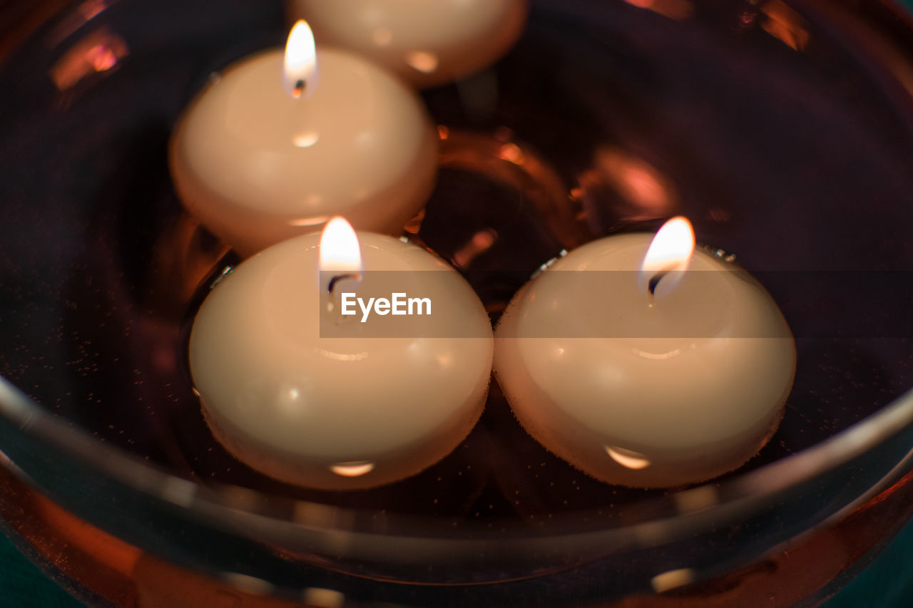 Close-up of illuminated candles in container