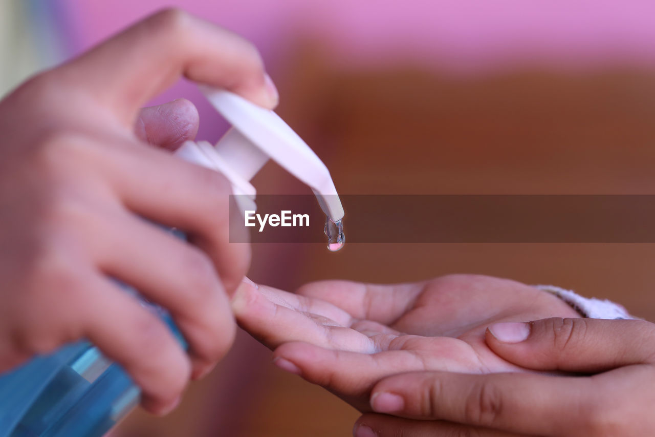 Hand cleaning with alcohol gel, pressing the alcohol bottle for taking care of physical health.