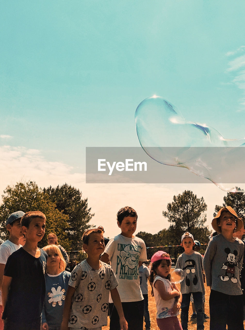 REAR VIEW OF PEOPLE PLAYING WITH BUBBLES