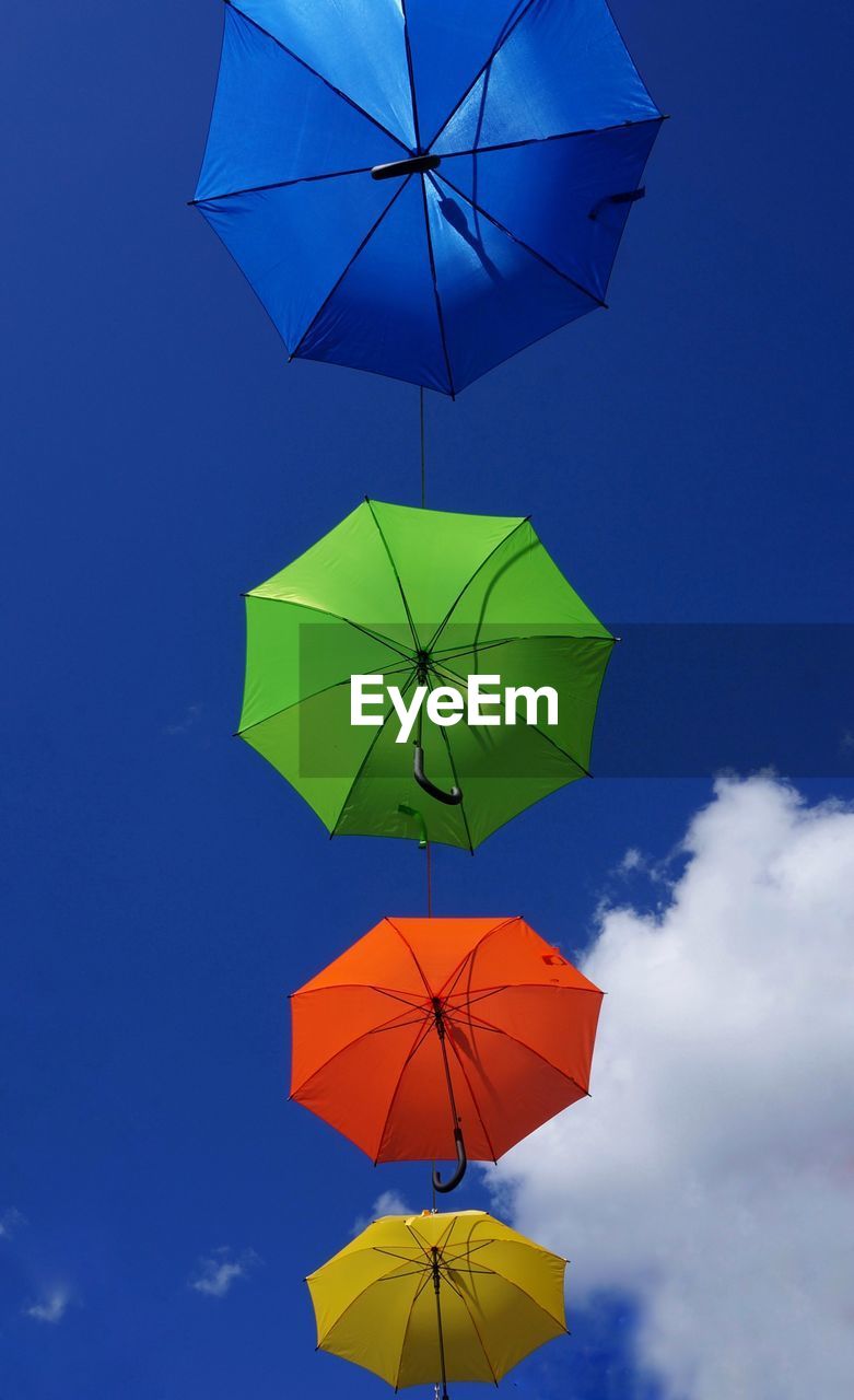 Low angle view of umbrellas hanging against sky