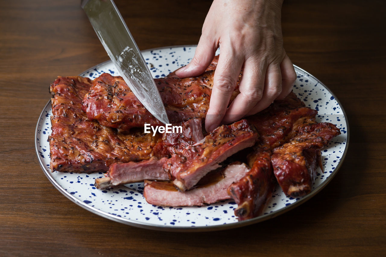 CLOSE-UP OF PERSON PREPARING FOOD ON PLATE