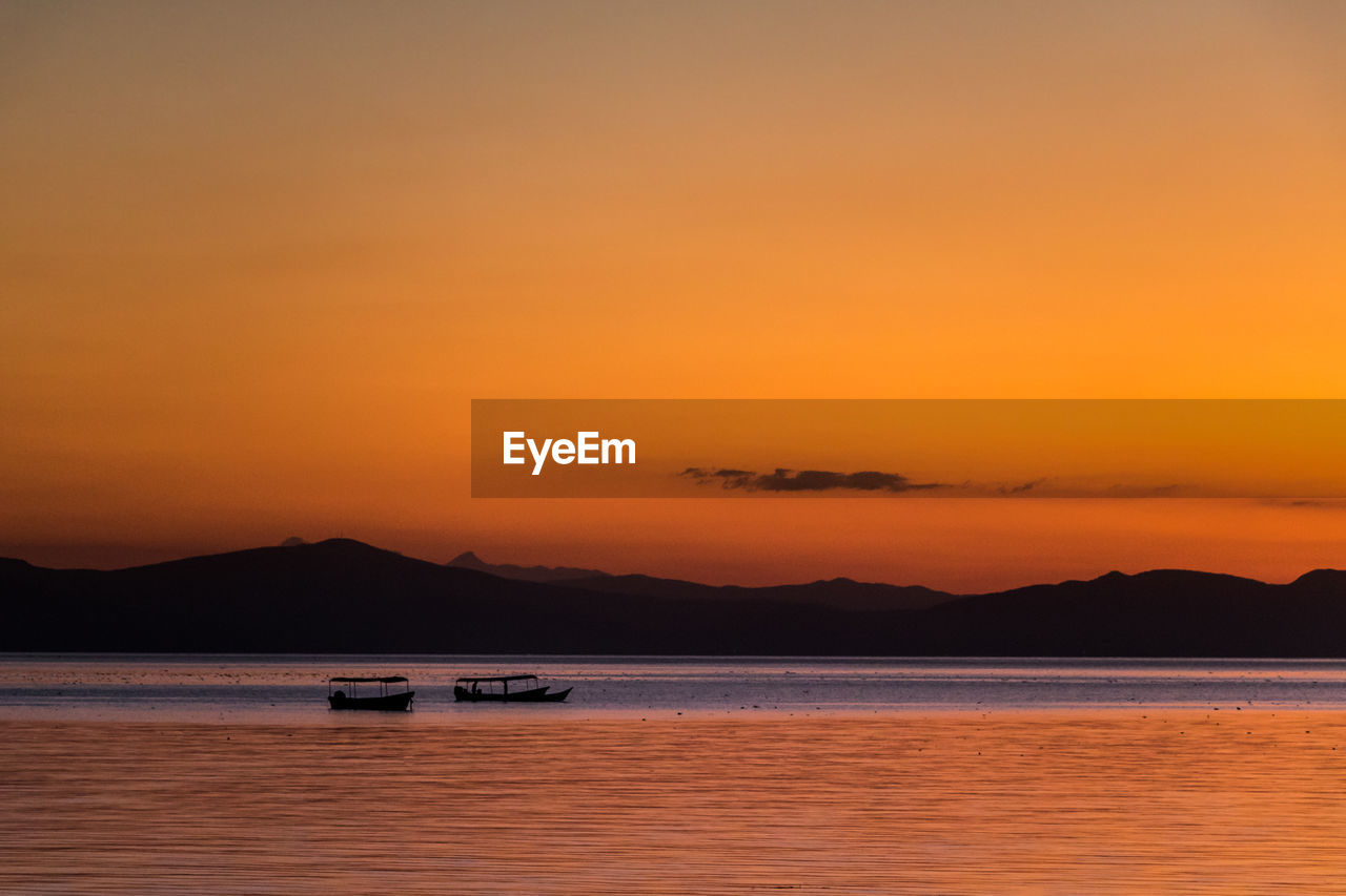 Silhouette of boats in sea during sunset