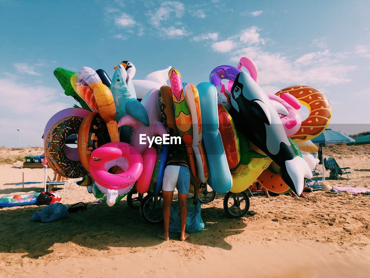 Multi colored toys on beach against sky. inflatables beach toys. man looking into the objects