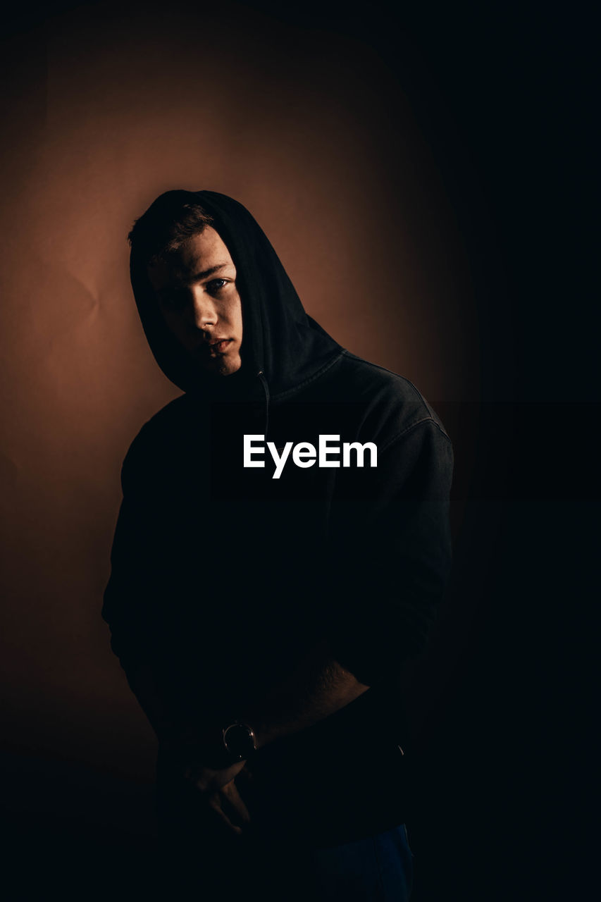 YOUNG MAN WEARING HAT AGAINST BLACK BACKGROUND