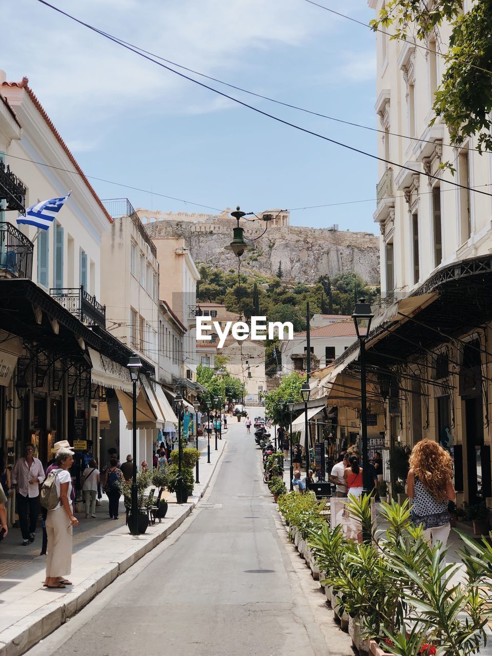 PEOPLE WALKING ON STREET AMIDST BUILDINGS AGAINST SKY