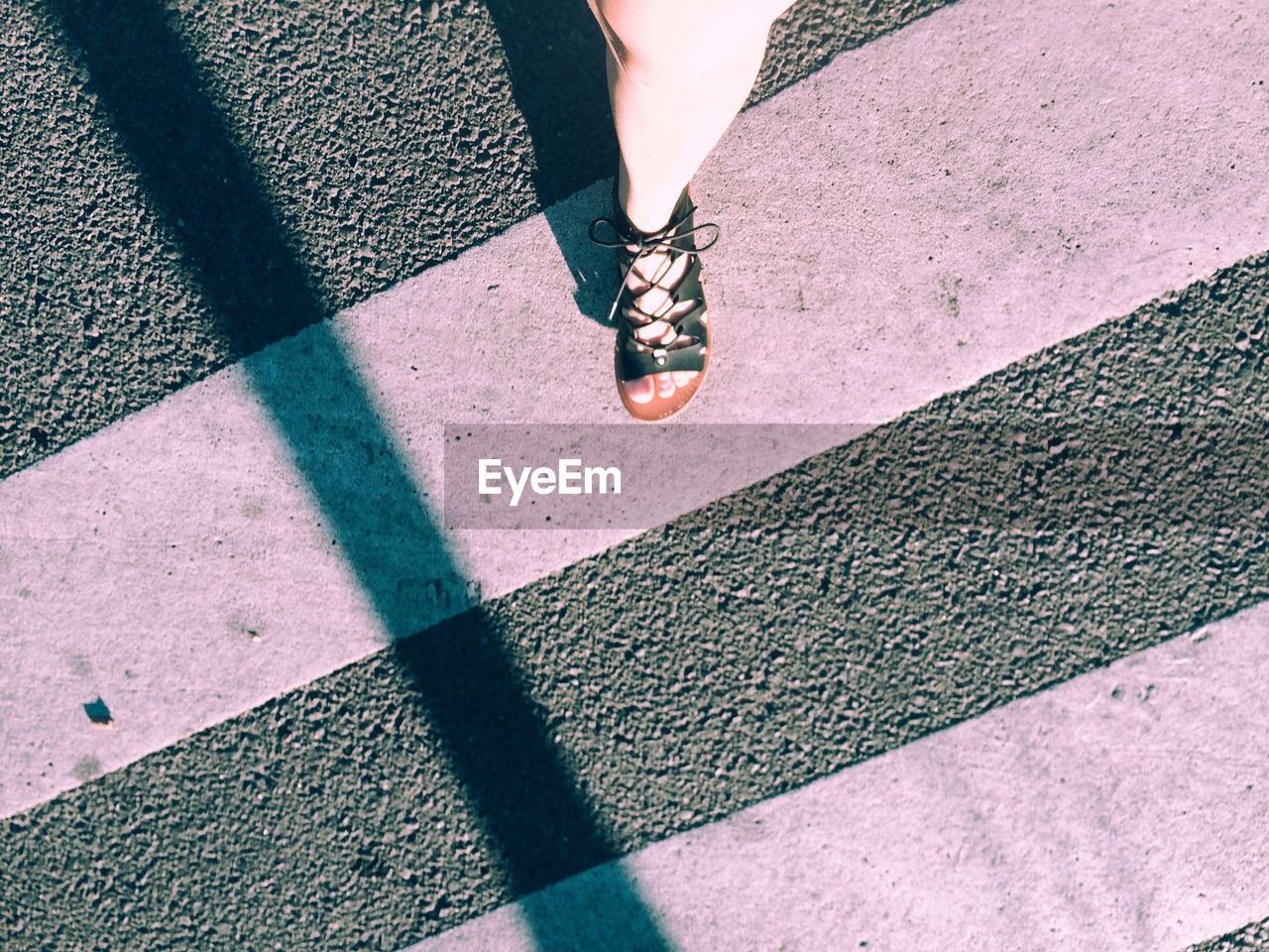 Low section of woman walking on zebra crossing