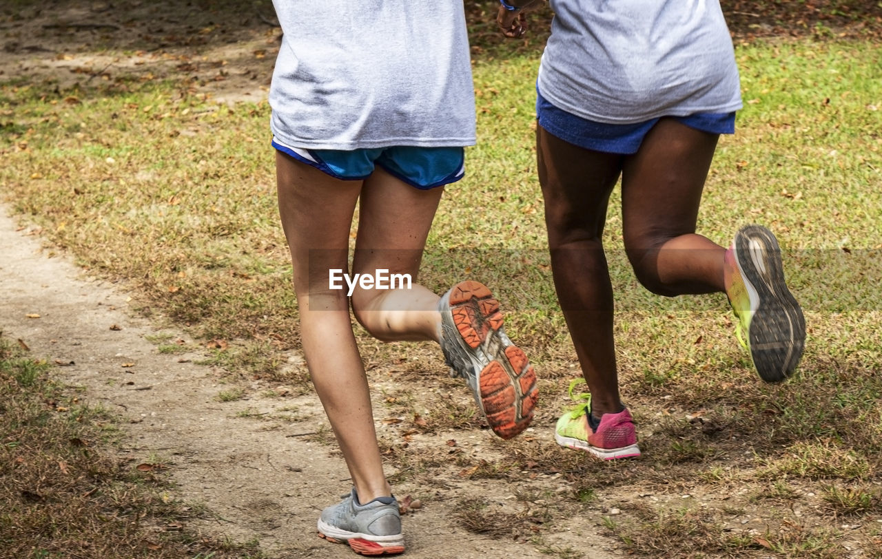 Low section of women running on dirt road