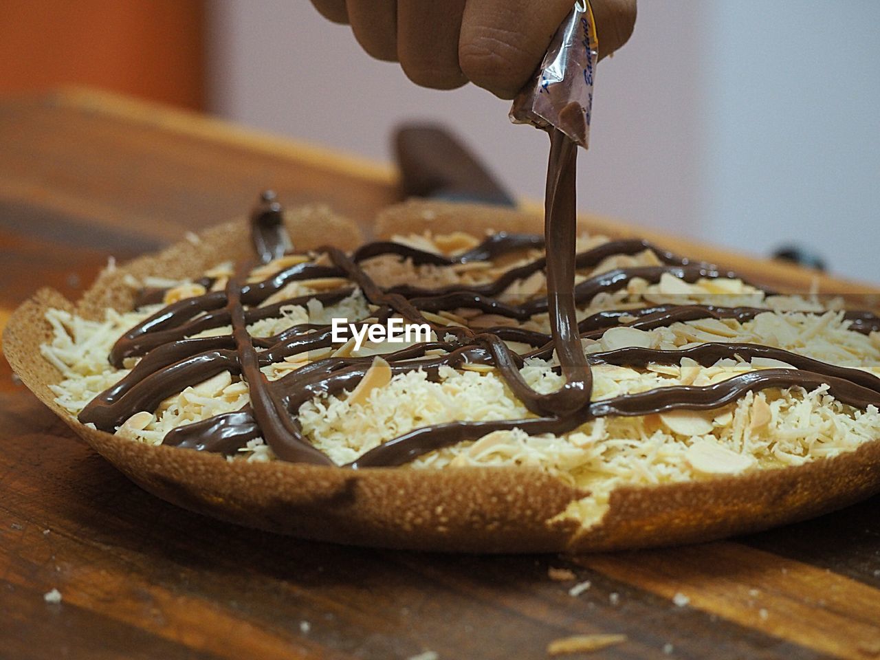 High angle view of man dripping chocolate sauce over pancake