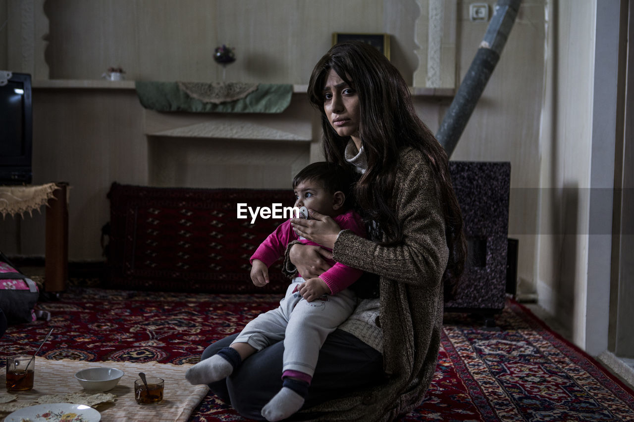 Portrait of woman with baby kneeling at home