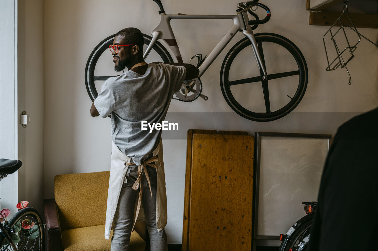 Rear view of male owner repairing bicycle in workshop