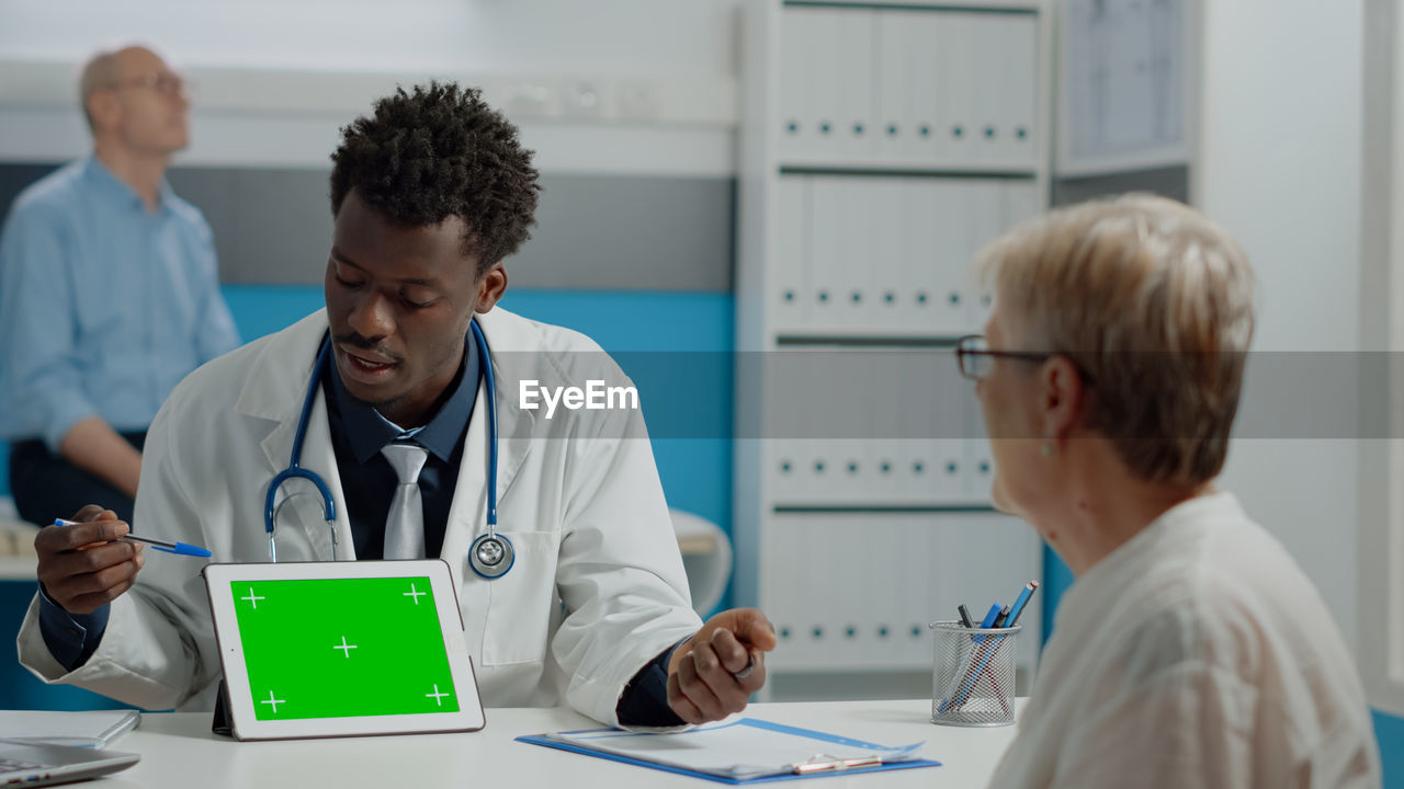 Doctor showing digital tablet to patient