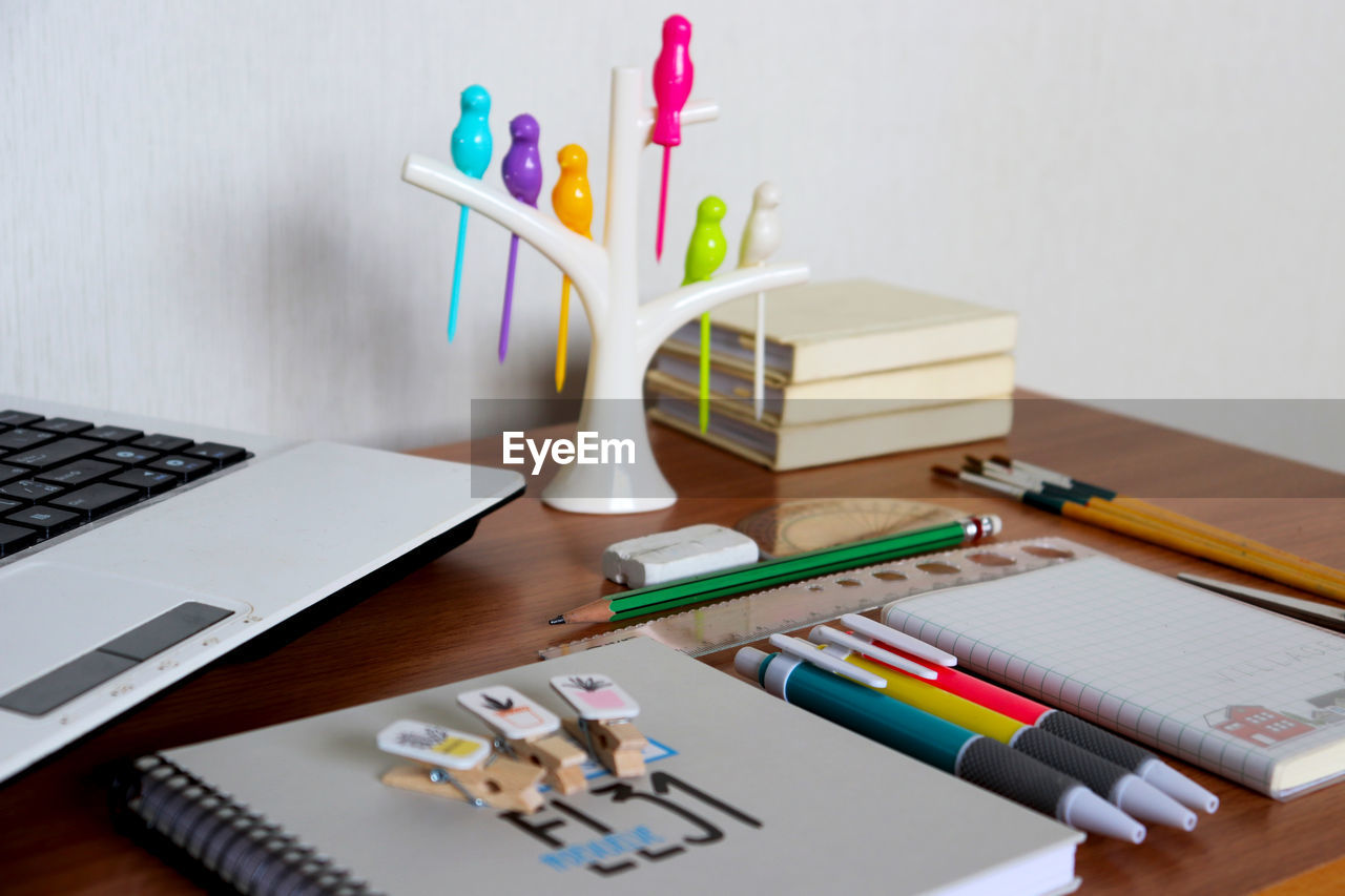 HIGH ANGLE VIEW OF MULTI COLORED PENCILS WITH BOOK AND TABLE