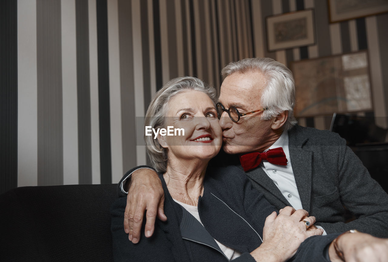 Senior man kissing wife on couch