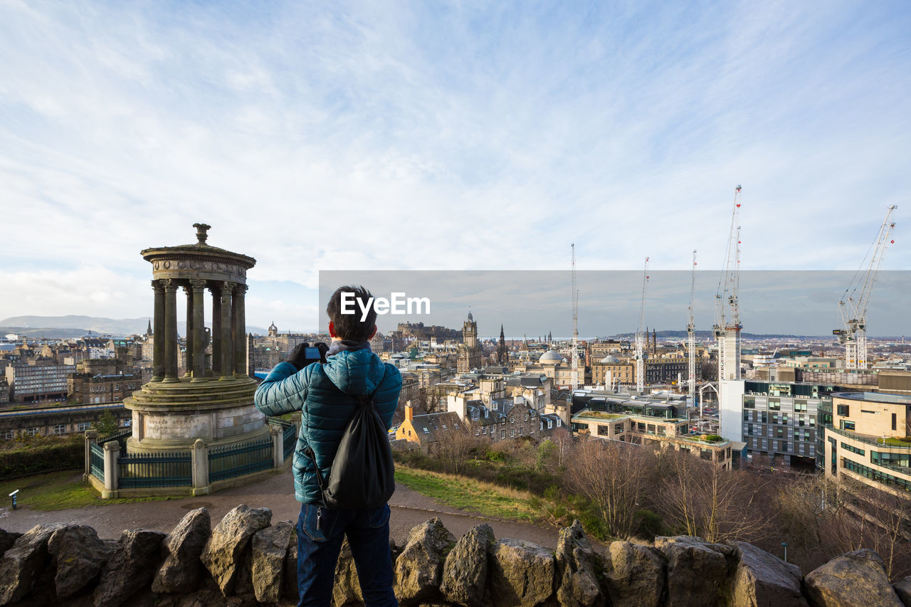 REAR VIEW OF MAN STANDING ON CITYSCAPE