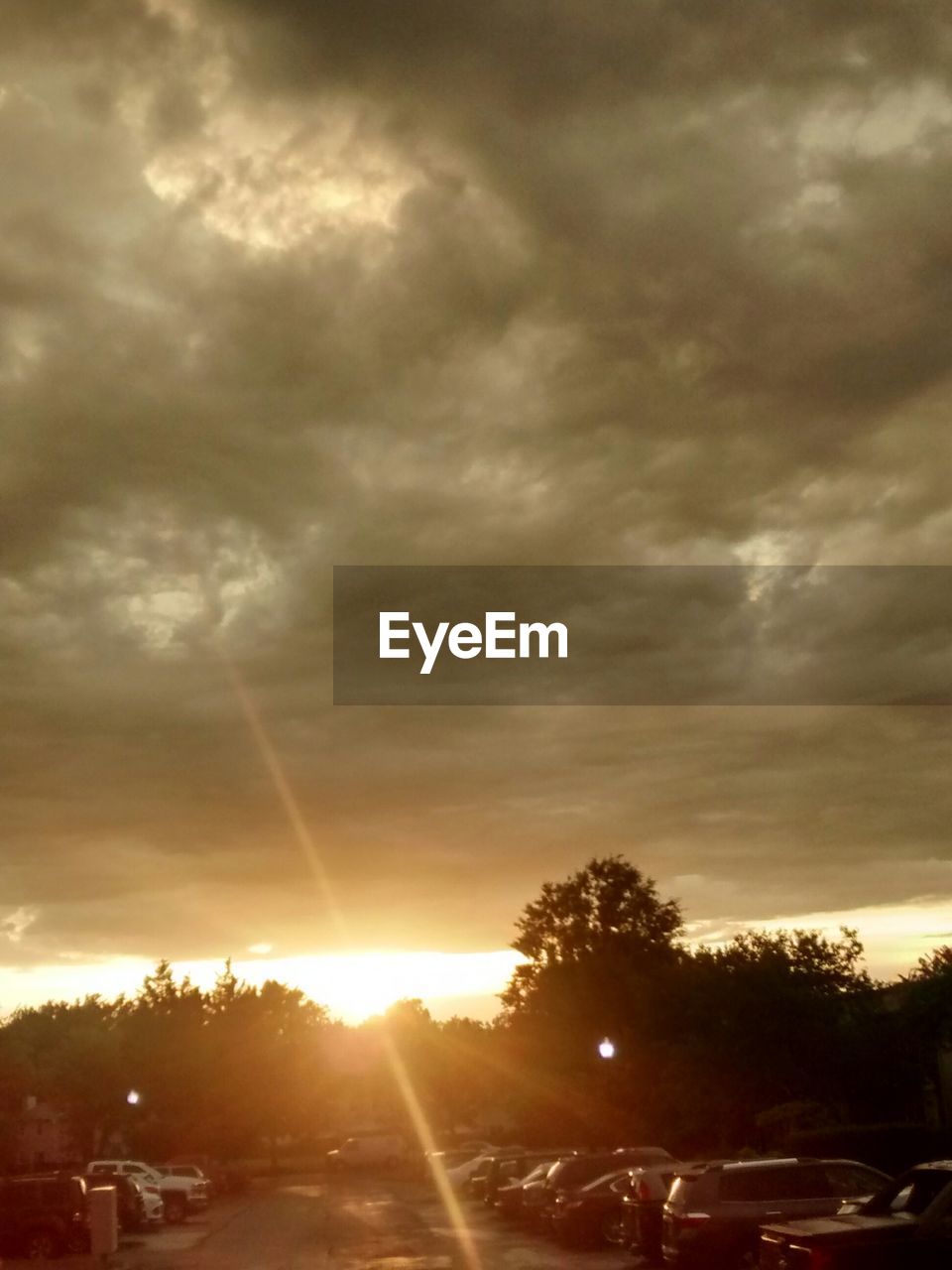 SUN SHINING THROUGH CLOUDS OVER ROAD