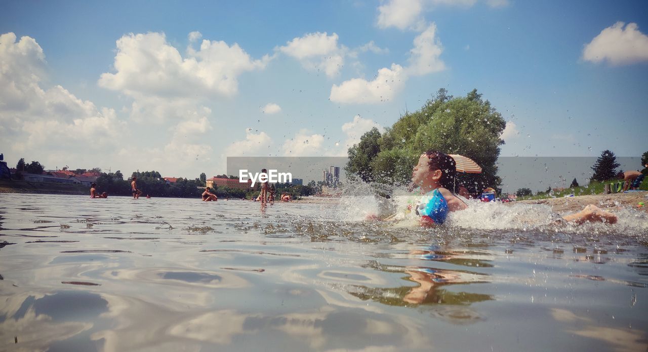 Side view of boy swimming in sea against sky