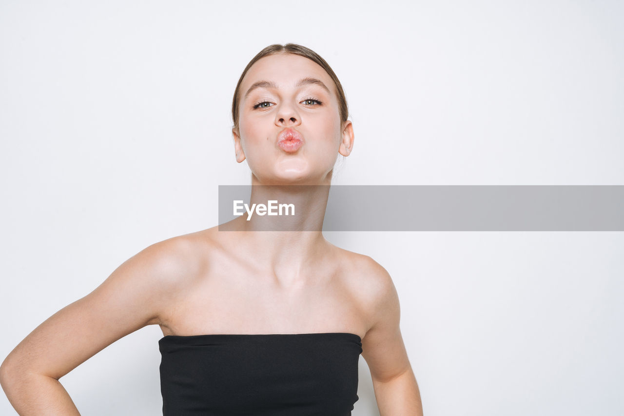 Beauty portrait of funny young girl with fresh skin tone showing kiss on white background