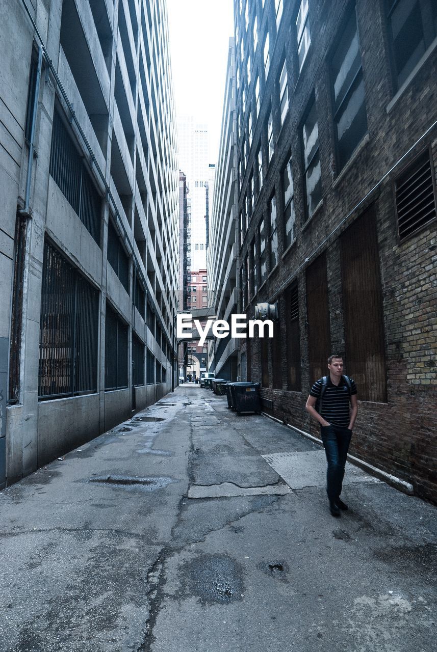 MAN ON ROAD AMIDST BUILDINGS