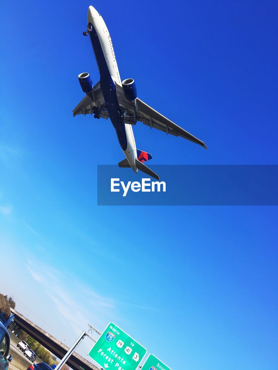 LOW ANGLE VIEW OF AIRPLANE FLYING IN CLEAR BLUE SKY