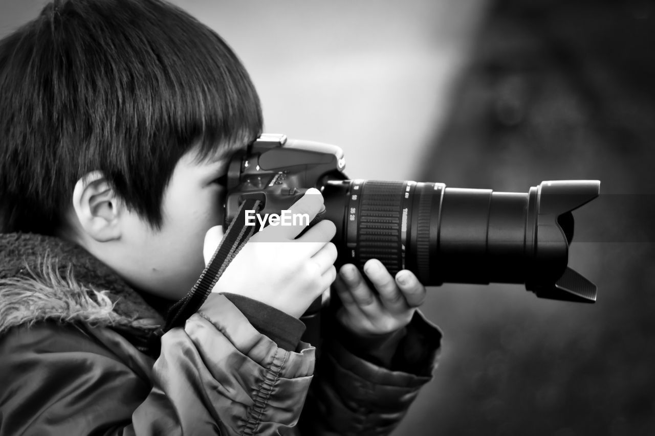 Side view of boy photographing with camera