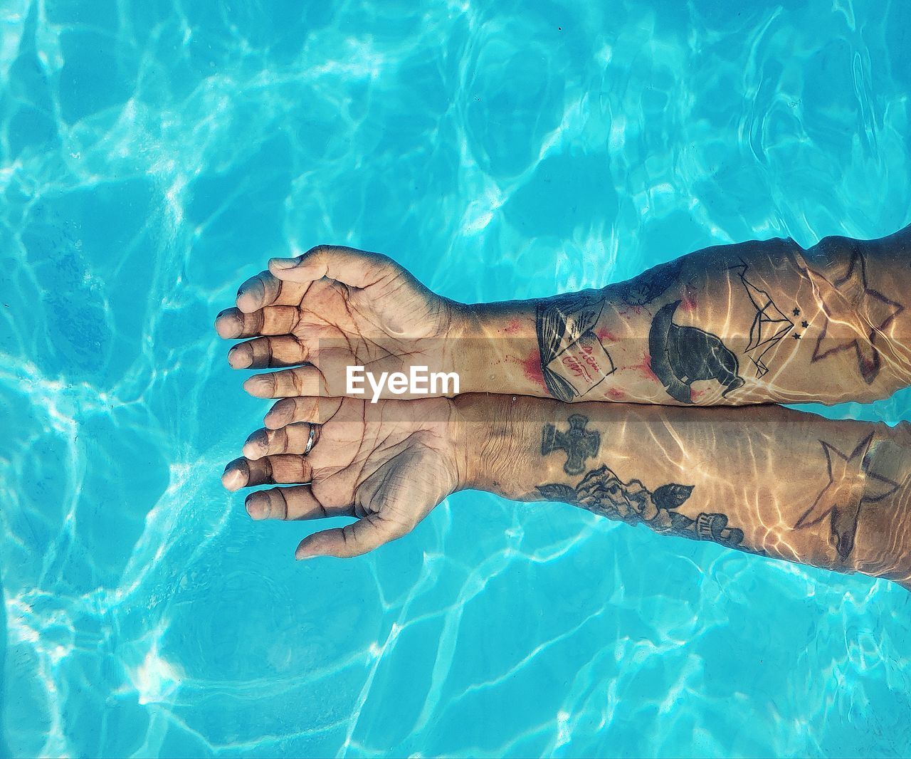 Cropped hands of woman with tattoos in swimming pool