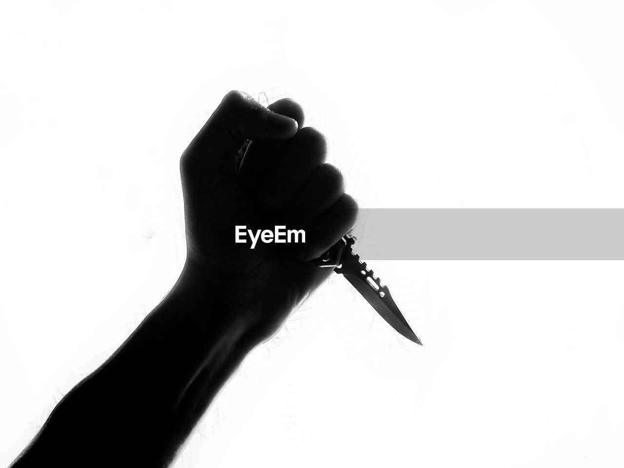 Low angle view of hand holding knife against clear sky