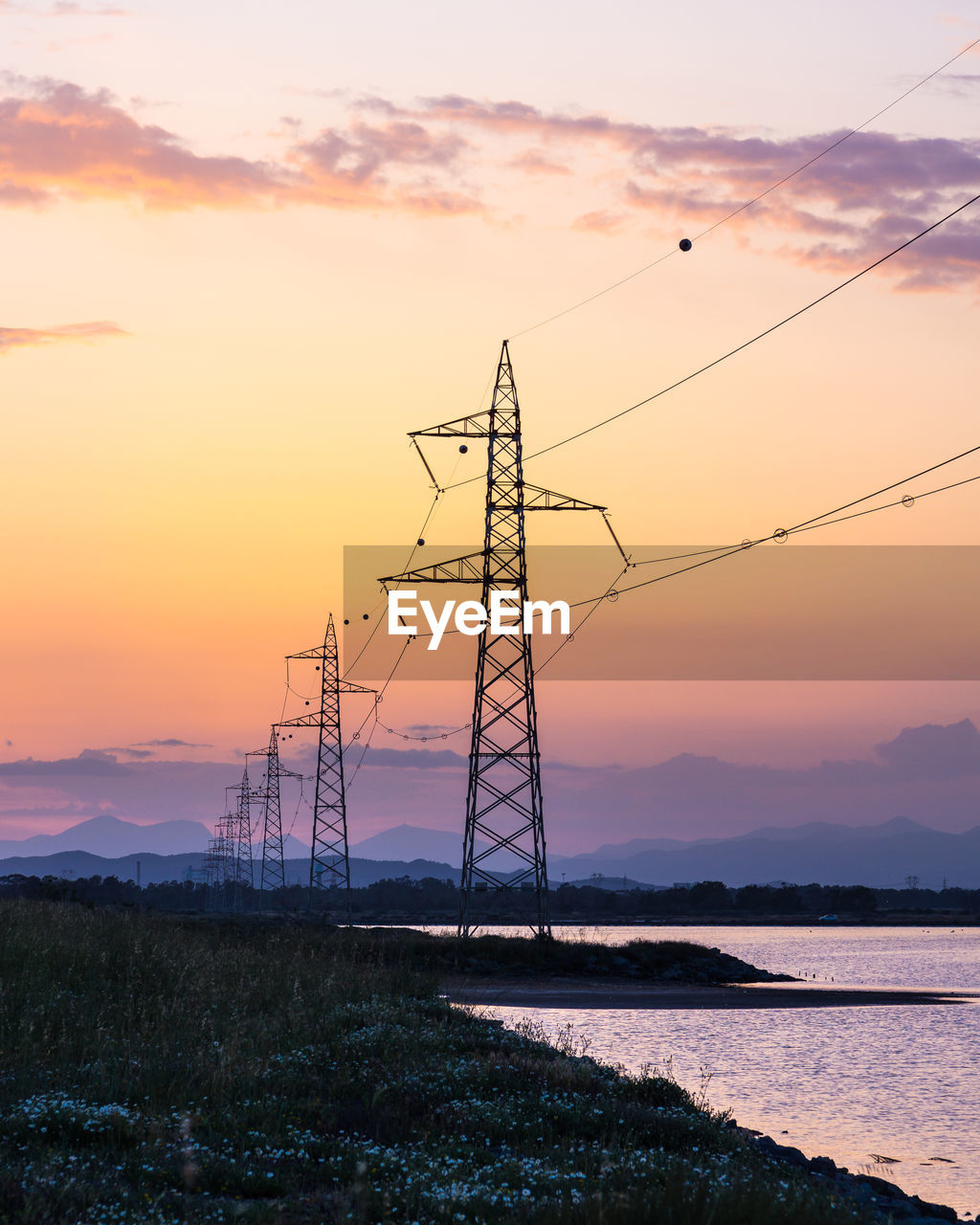 Power lines at sunset on lake