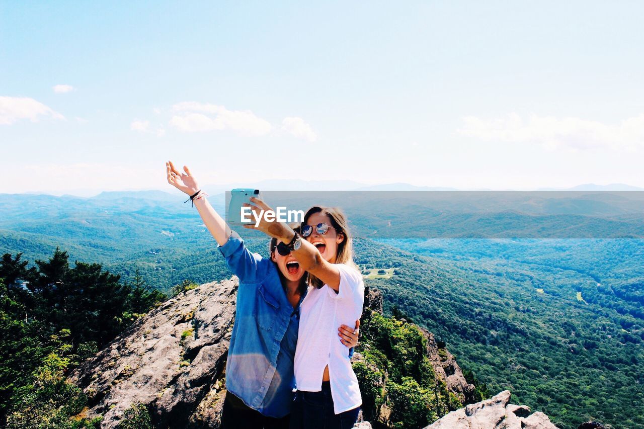 Young women taking selfie on mountain against sky