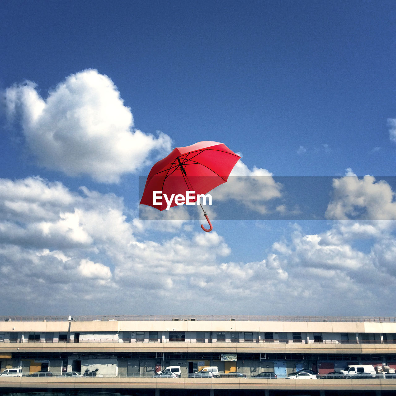 Low angle view of red umbrella in mid-air against sky