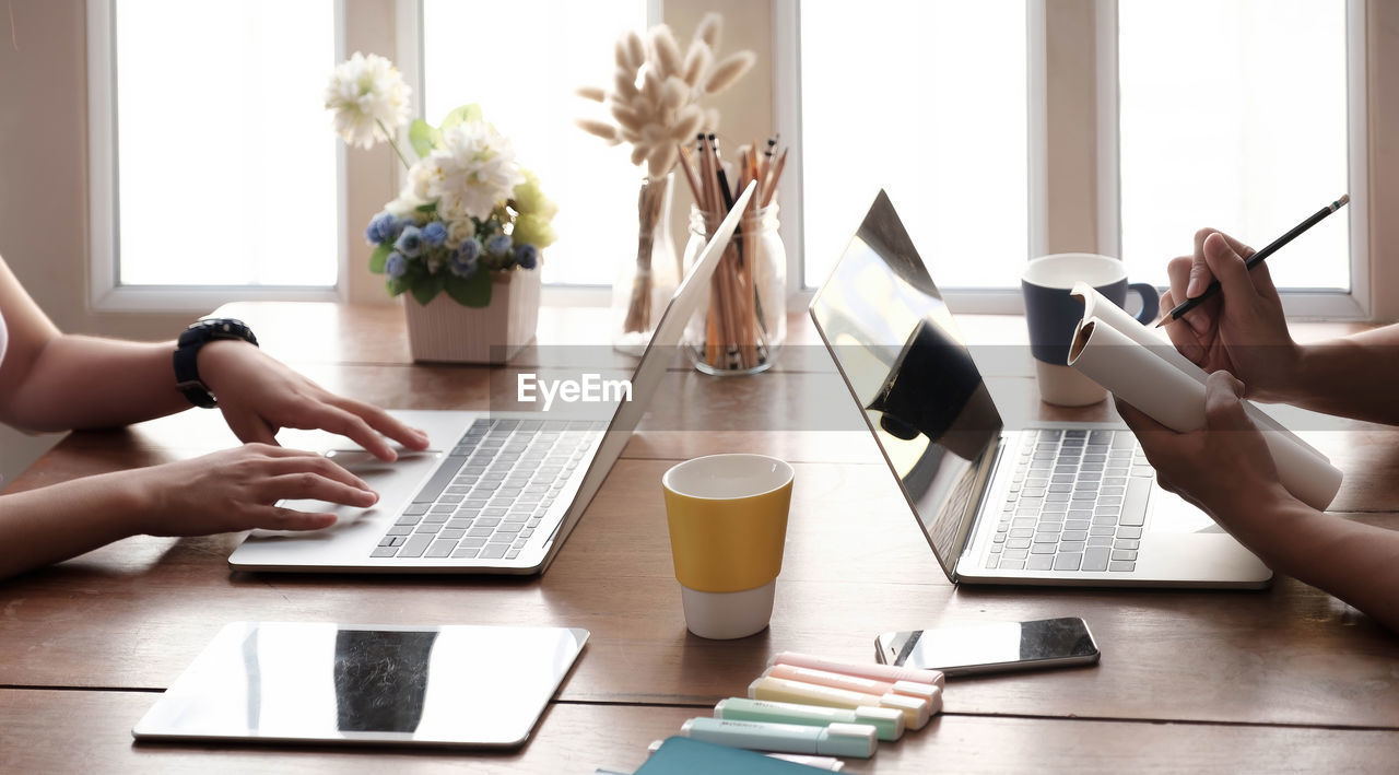 MIDSECTION OF WOMAN USING LAPTOP ON TABLE AT HOME