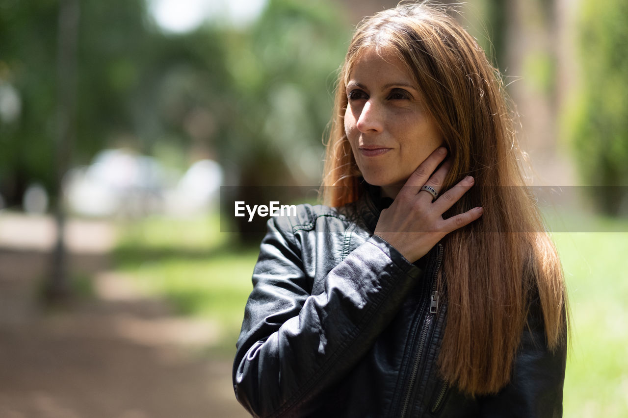 Smiling beautiful woman wearing leather jacket while looking away