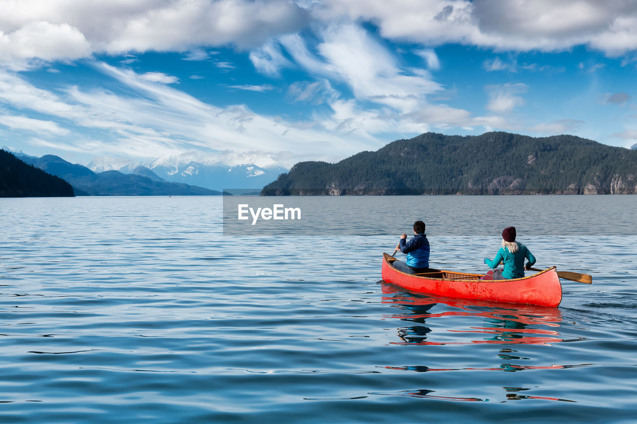 PEOPLE ON LAKE AGAINST SKY