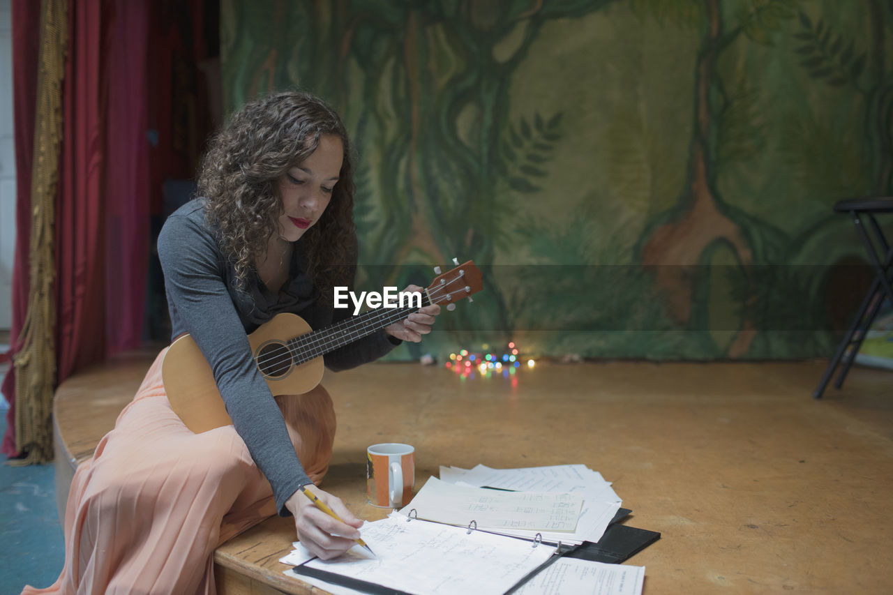 Young female musician composing music with the ukulele