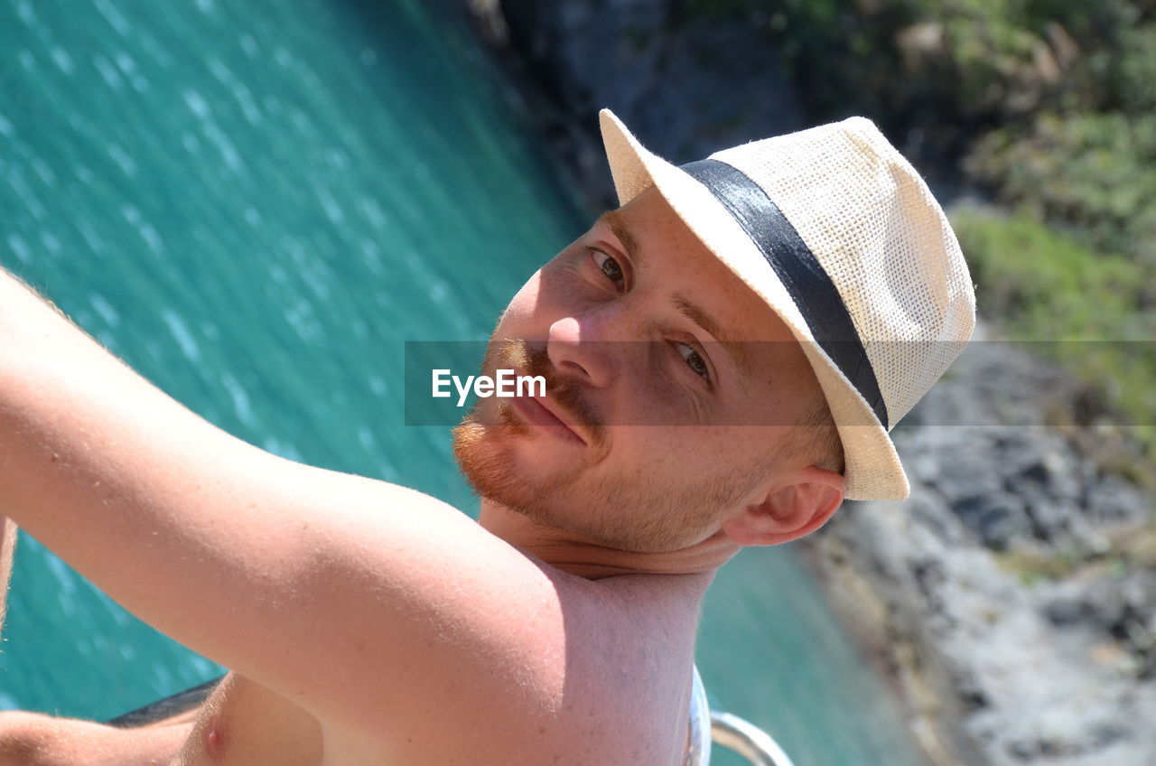 Close-up portrait of man wearing hat against sea