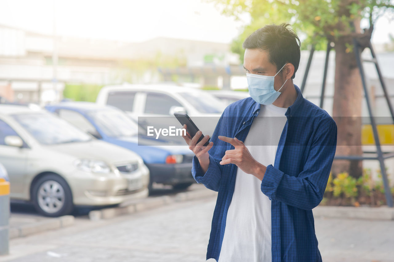 FULL LENGTH OF MAN USING PHONE ON STREET