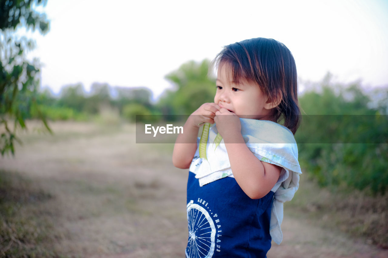 Girl eating green pea while standing on land