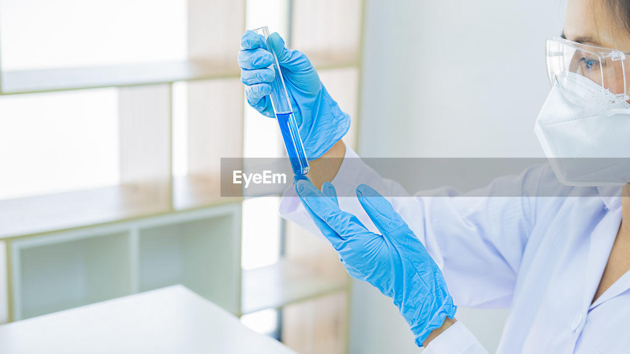 MIDSECTION OF PERSON HOLDING BLUE UMBRELLA