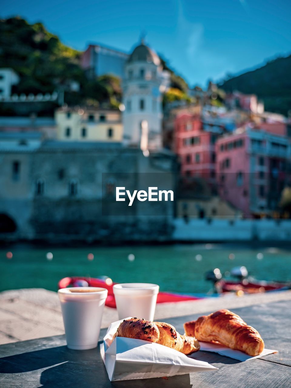 Croissant with coffee on table against buildings in city