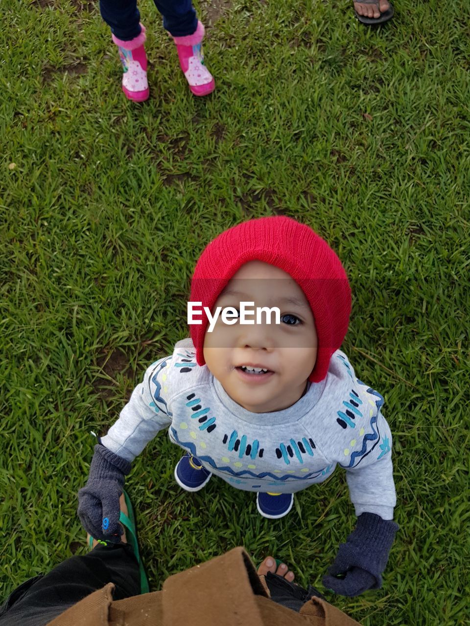 High angle portrait of smiling boy standing by father on grass