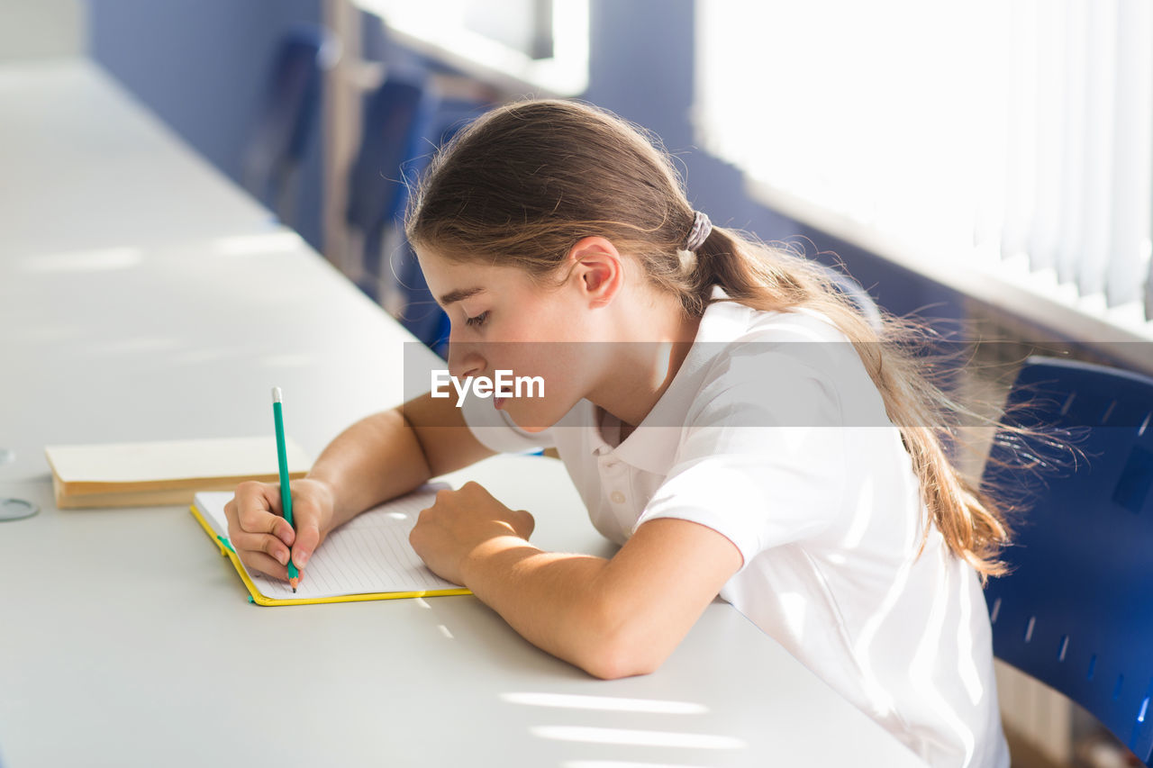 side view of boy drawing on book at home