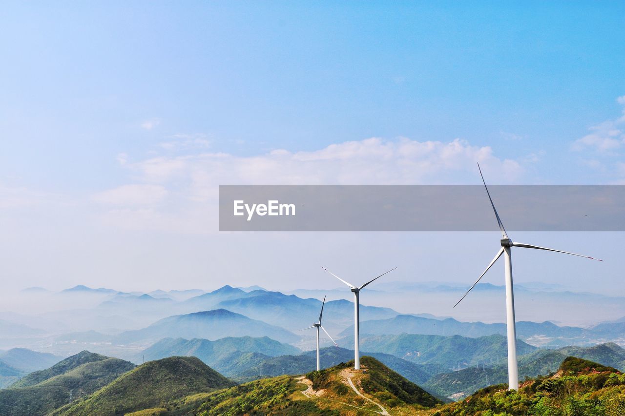 Wind turbines in mountains against blue sky