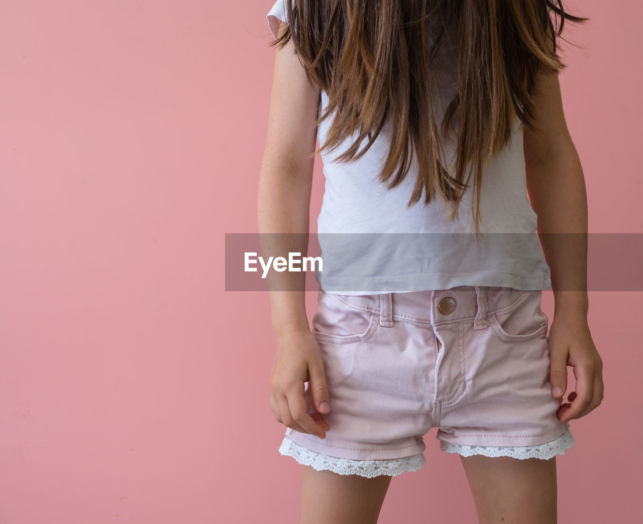 Midsection of girl standing against colored background