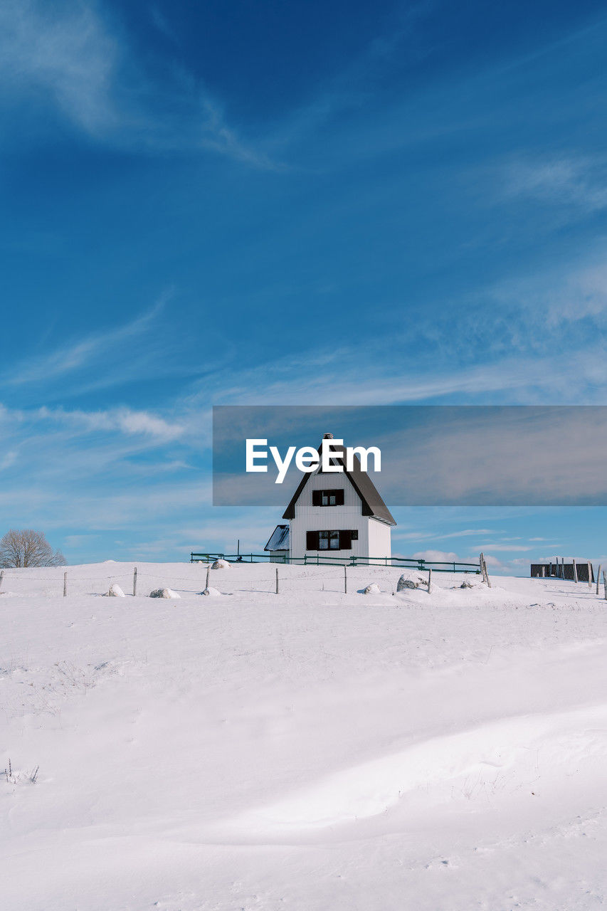 house on snow covered landscape against sky