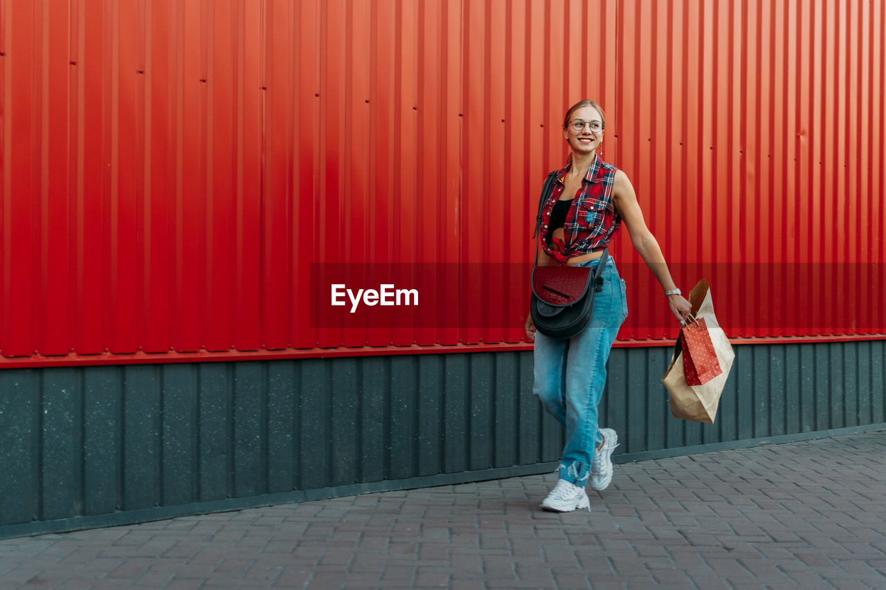 Full length of woman walking against red wall outdoors