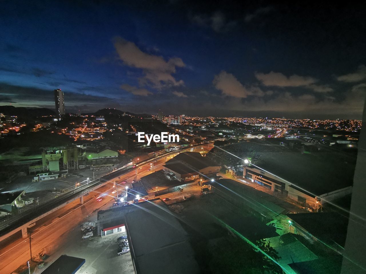 HIGH ANGLE VIEW OF ILLUMINATED STREET AMIDST BUILDINGS AT NIGHT