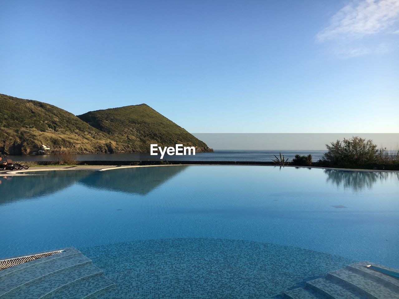 Swimming pool by sea against sky