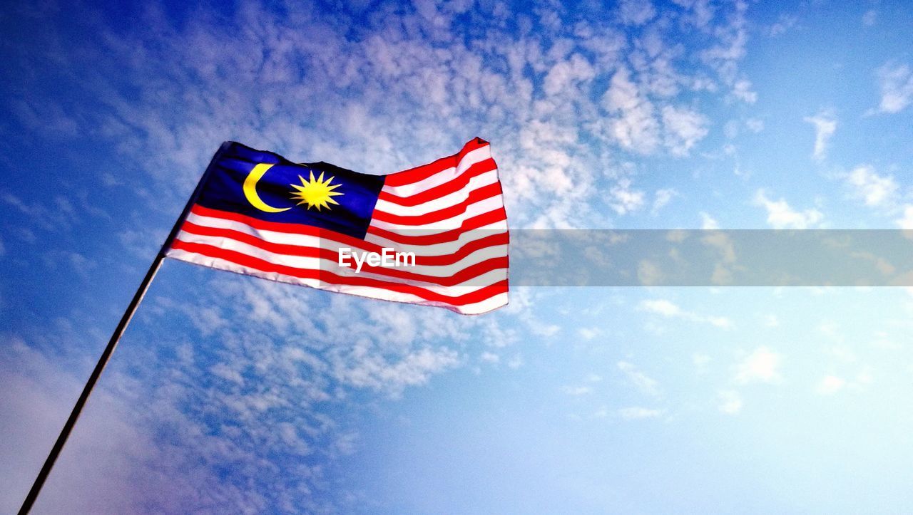 Low angle view of malaysian flag against blue sky