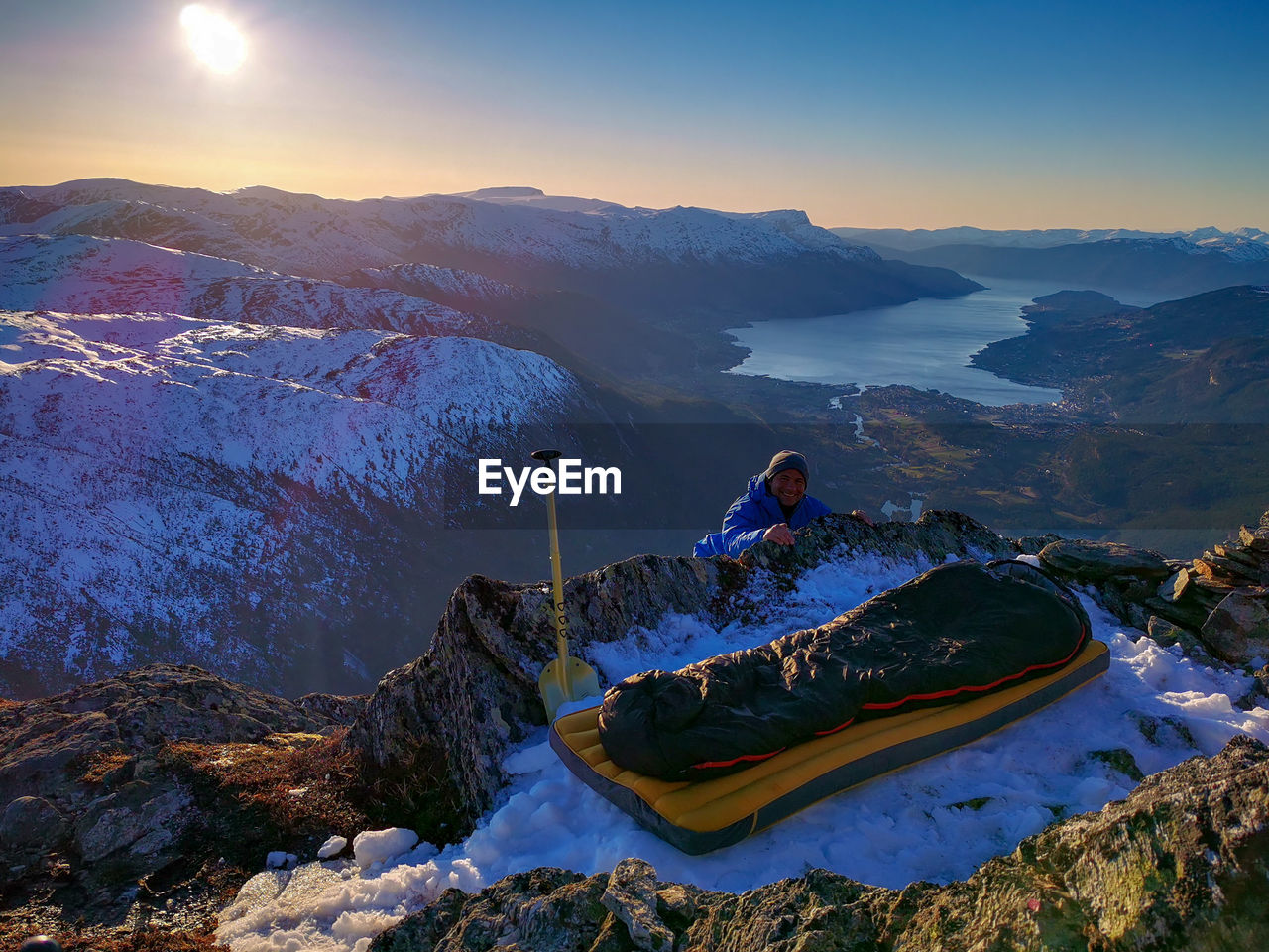 Explorer and sleeping bag on top of snow capped mountain 
