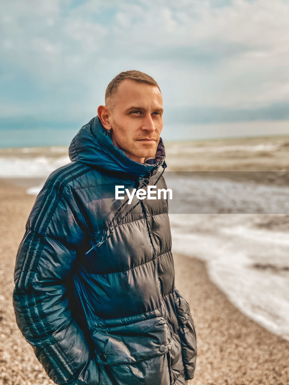 Portrait of mature man standing at beach against sky