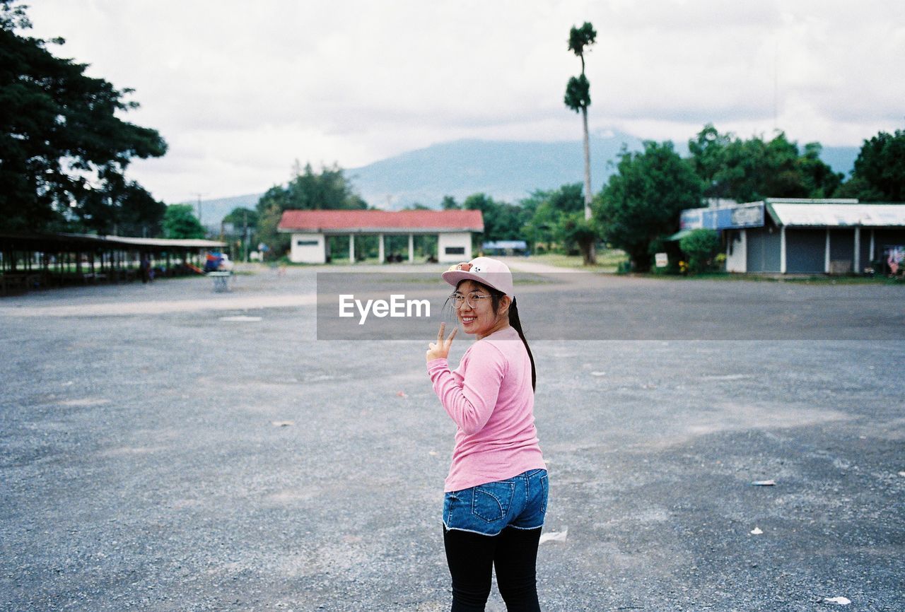 Smiling young woman standing in city against sky